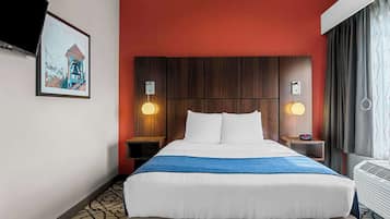 Une chambre d’hôtel avec un grand lit, deux tables de chevet, un téléviseur fixé au mur et un tableau encadré.