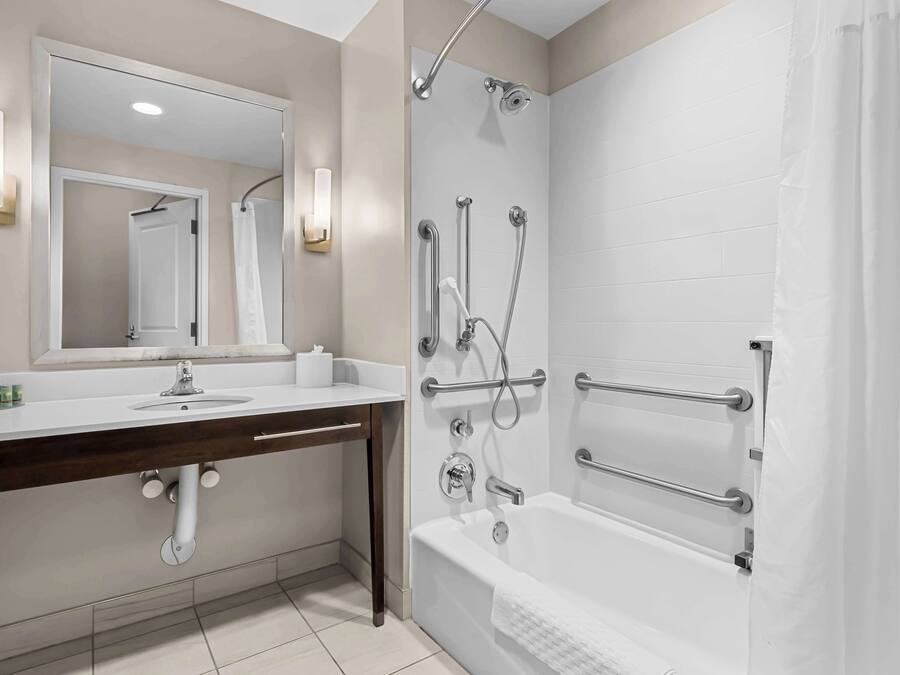 Une salle de bain moderne avec un lavabo blanc, un miroir et un espace douche.