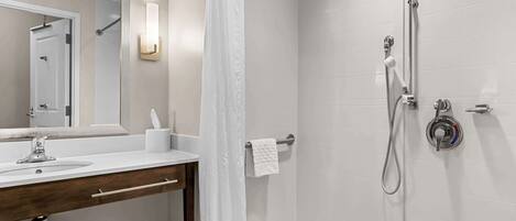 Un baño moderno con lavamanos blanco, espejo y zona de ducha.