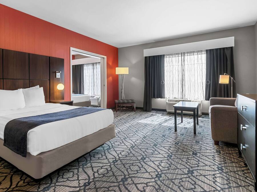 A hotel room with a large bed, a desk, a chair, a dresser, and a TV.