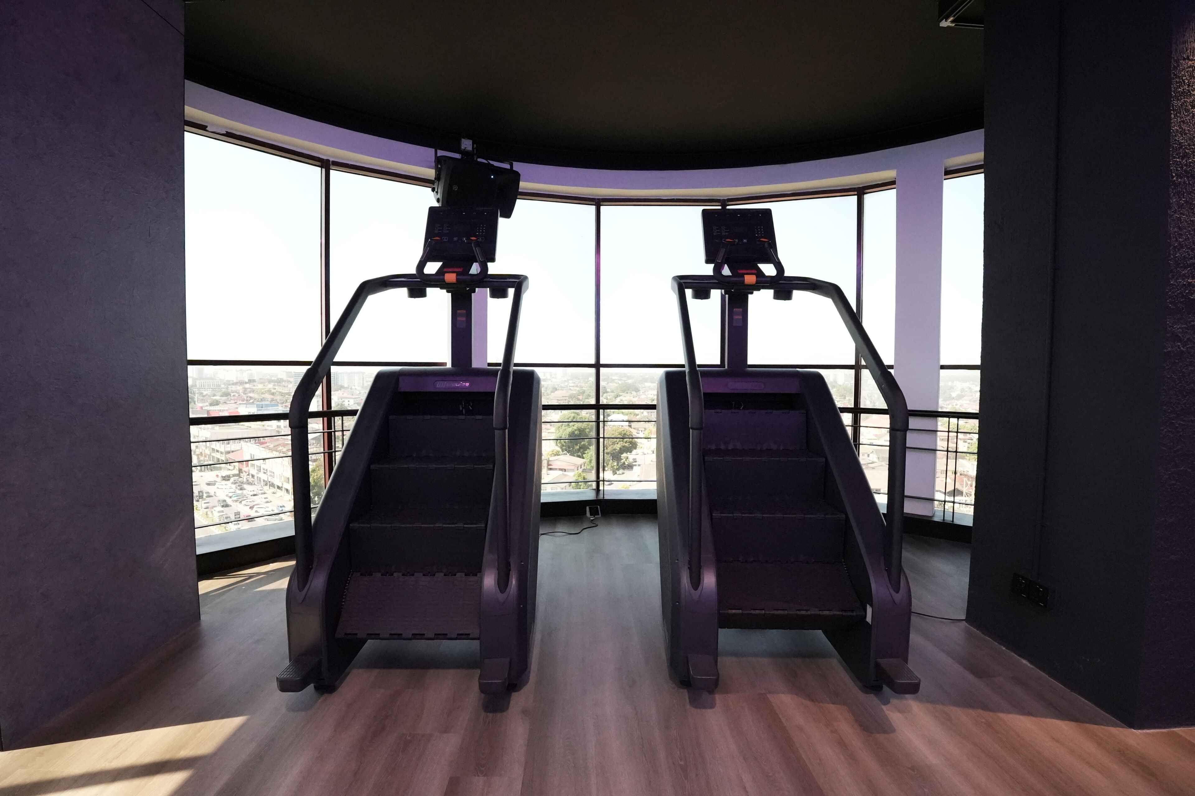 Une salle de sport équipée de deux tapis de course et dotée de grandes fenêtres donnant sur la ville.