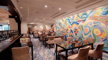 A hotel lobby with a bar area, seating, and a colorful mural on the wall.