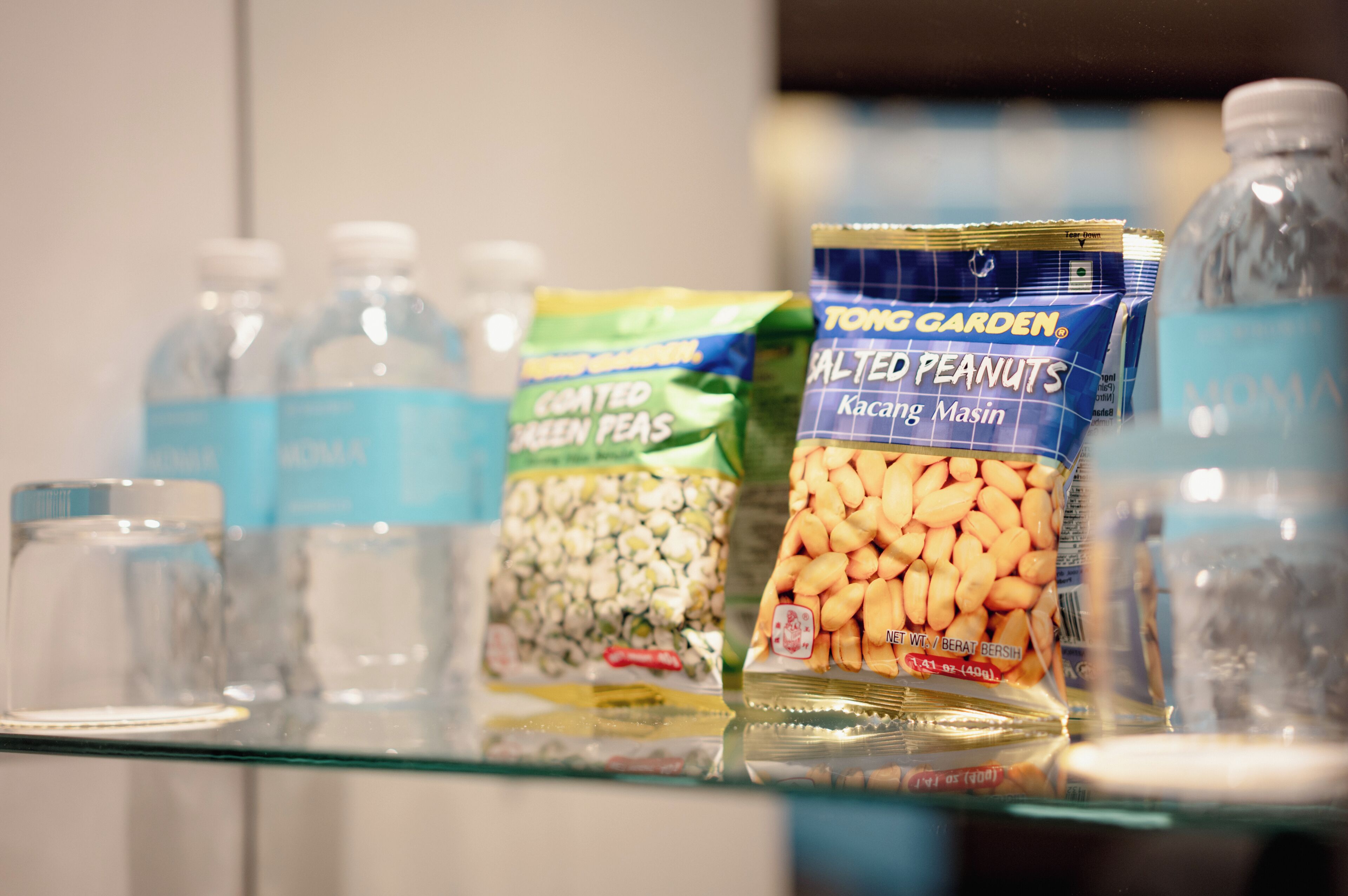A shelf with various food items including a bag of salted peanuts, a bottle of water, and other packaged goods.