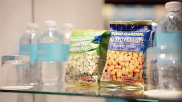 A shelf with various food items including a bag of salted peanuts, a bottle of water, and other packaged goods.