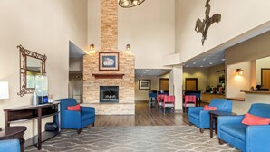 A hotel lobby with a fireplace, seating area, and a dining space.