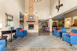 A hotel lobby with a fireplace, seating area, and a dining space.