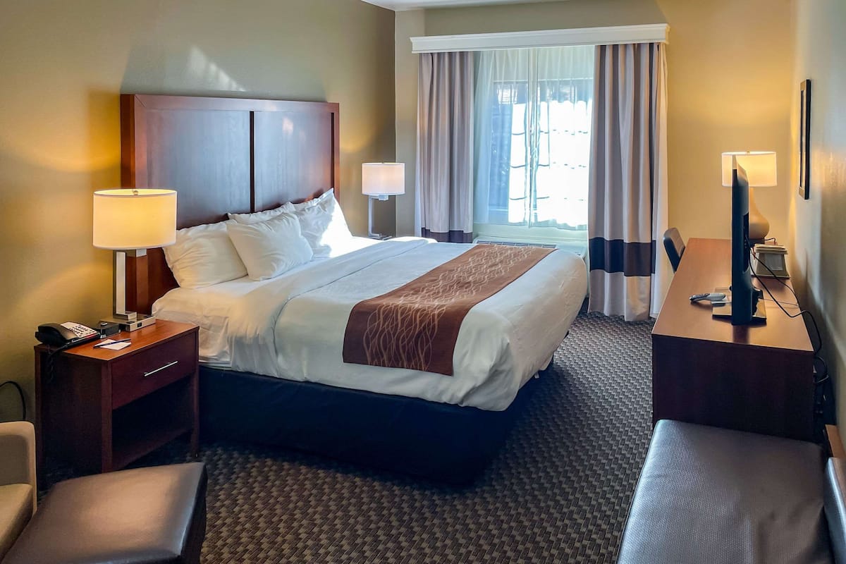 A hotel room with a large bed, bedside tables, a desk, and a chair.