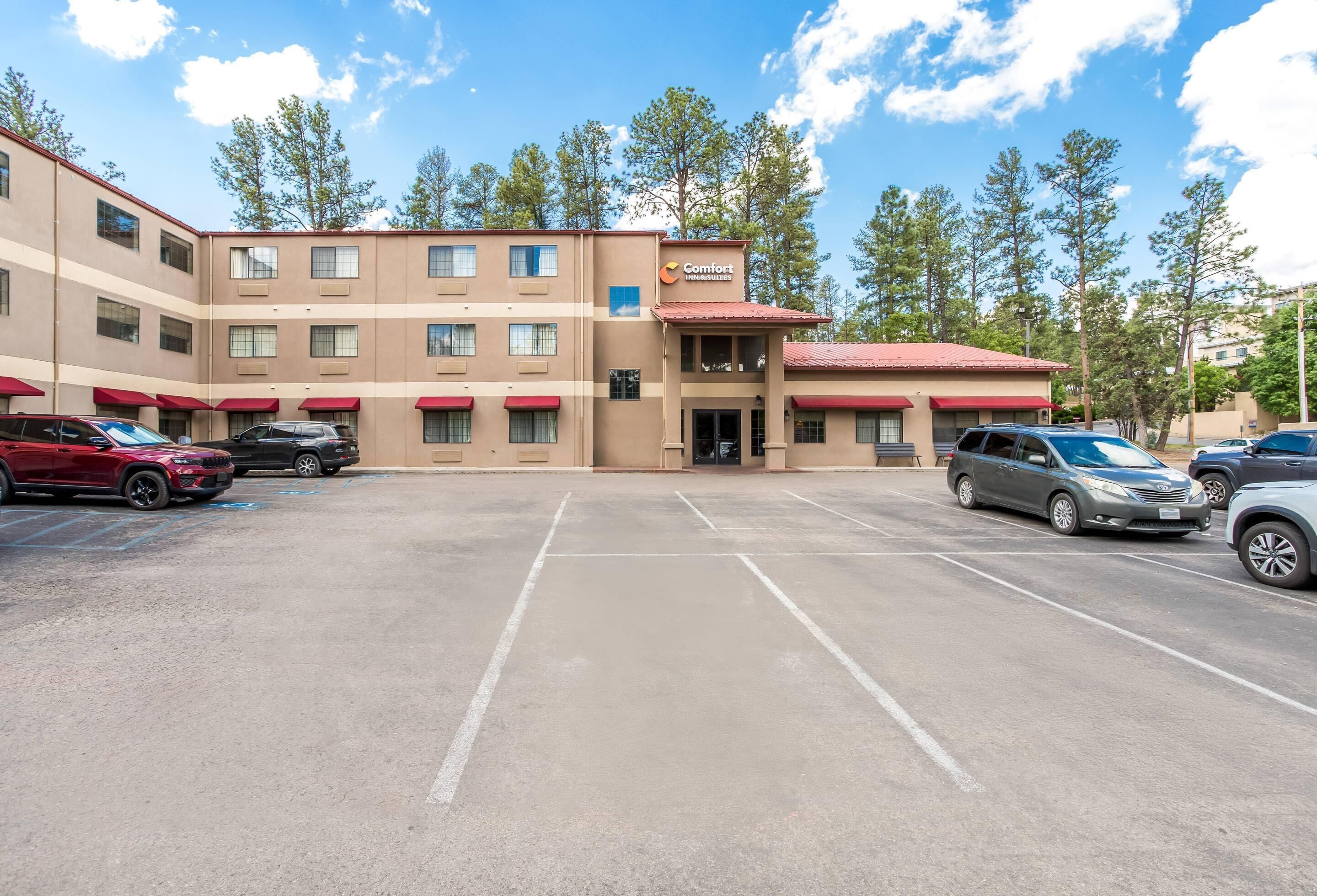 A multi-story hotel with a parking lot, featuring a central entrance and multiple windows.