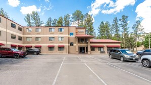A multi-story hotel with a parking lot, featuring a central entrance and multiple windows.