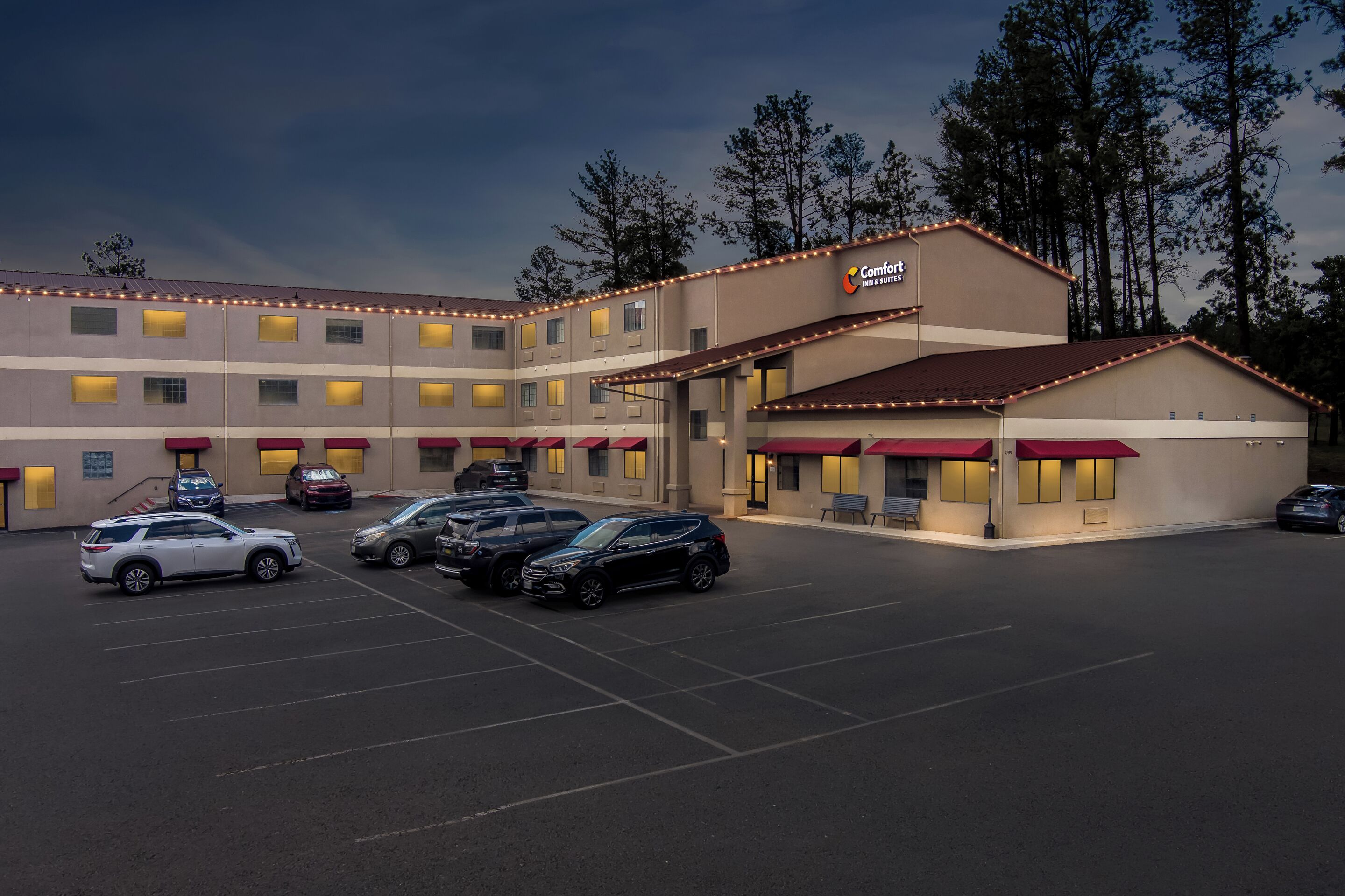 A hotel with a parking lot, multiple vehicles, and a building with a sign.