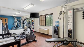 A gym with exercise equipment, a water dispenser, and a mirror.