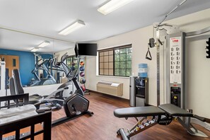 A gym with exercise equipment, a water dispenser, and a mirror.