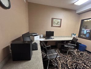 A hotel room with a desk, two chairs, a printer, a computer, and a clock on the wall. - Sylvania Inn & Suites Tigard Portland I-5 (Portland)