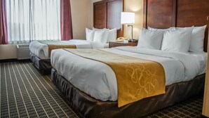 A hotel room with two beds, a large window with curtains, a bedside table with a lamp, and a patterned carpet. - Comfort Suites Portland Southwest (Portland)