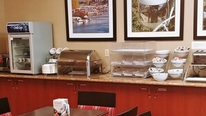 A restaurant with a counter, buffet, and framed pictures on the wall. - Comfort Suites Portland Southwest (Portland)