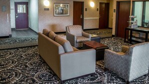 A hotel lobby with a sofa, armchairs, a coffee table, and a chandelier. There are doors and a painting on the wall. - Comfort Suites Portland Southwest (Portland)