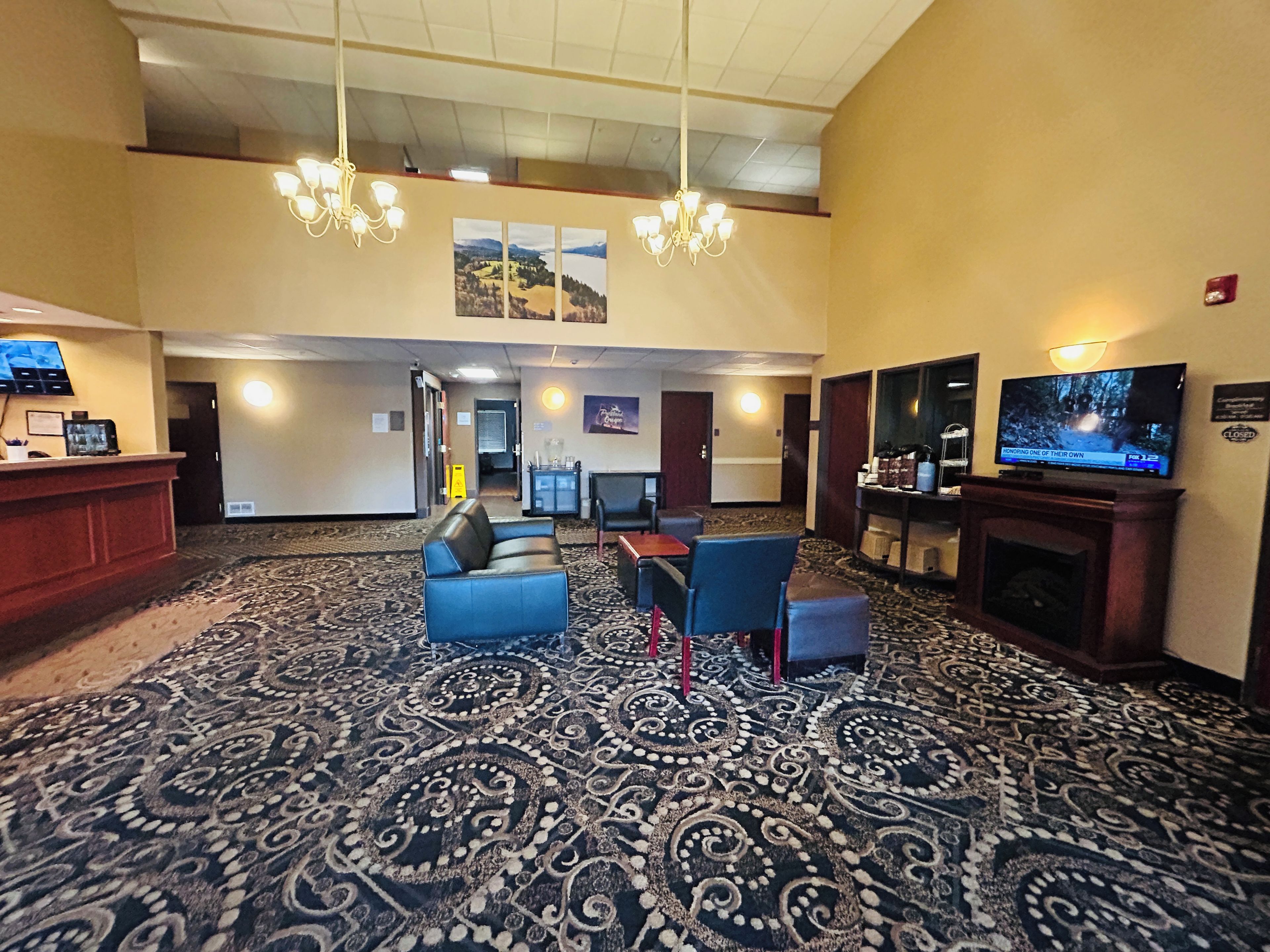 A hotel lobby with a reception desk, seating area, television, and a fireplace.