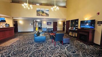 A hotel lobby with a reception desk, seating area, television, and a fireplace.