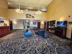 A hotel lobby with a reception desk, seating area, television, and a fireplace. - Sylvania Inn & Suites Tigard Portland I-5 (Portland)