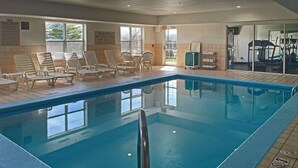 An indoor swimming pool with clear pool rules and a lifeguard warning sign, surrounded by lounge chairs and exercise equipment. - Quality Inn & Suites Cincinnati Sharonville (Sharonville)