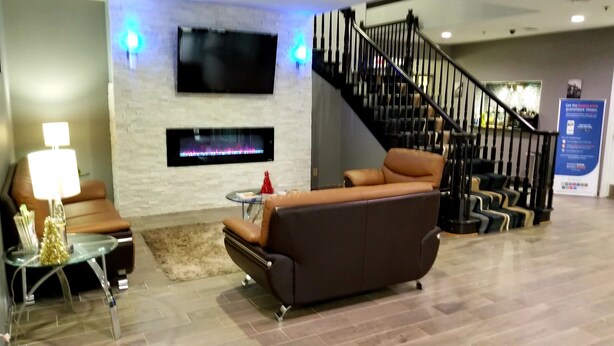 A modern lobby with a fireplace, leather sofas, a TV, and a staircase. - Quality Inn & Suites Cincinnati Sharonville (Sharonville)