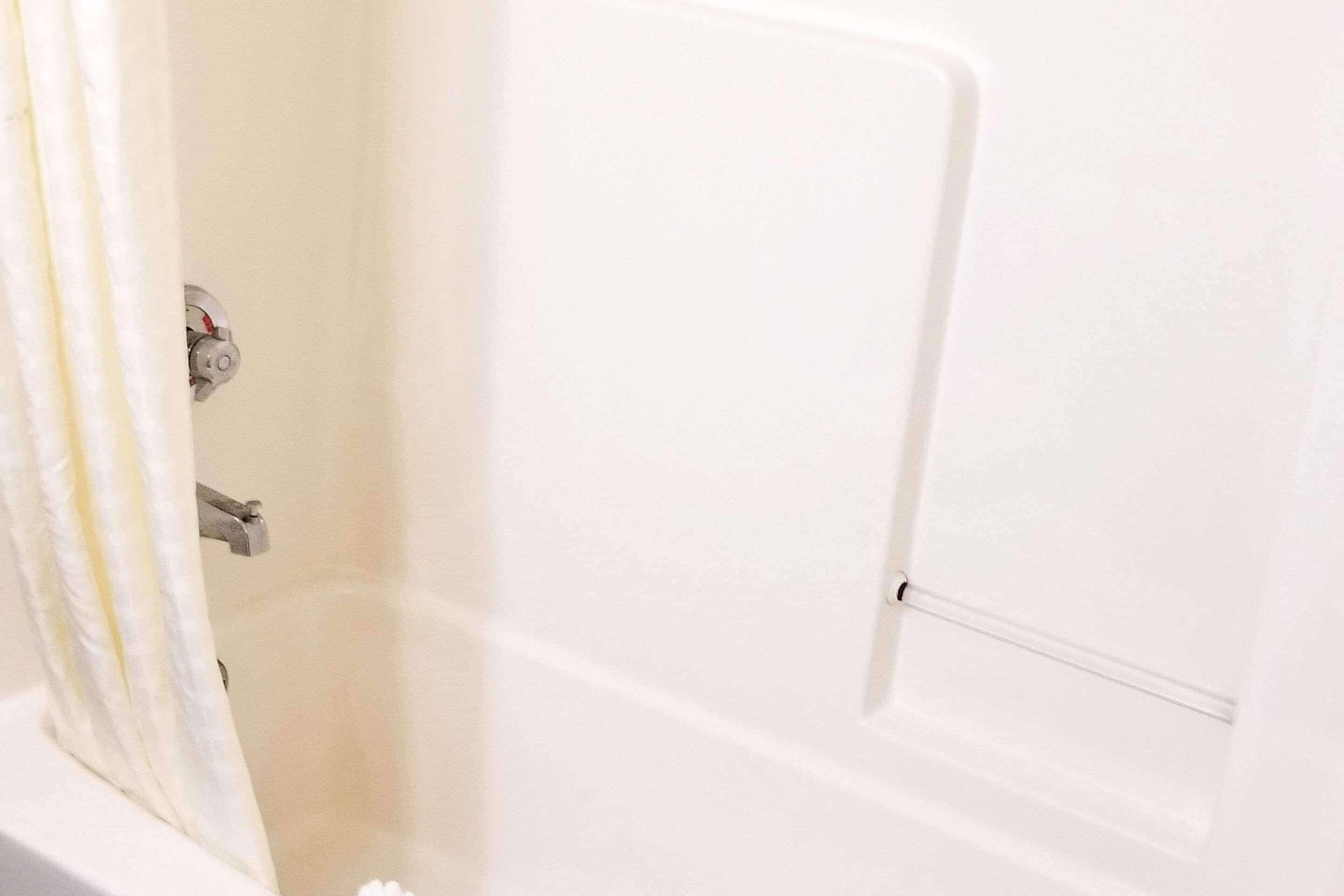 A white bathtub with a shower curtain partially drawn back.