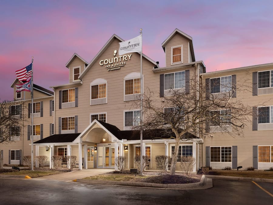 A multi-story hotel with a sign reading "Country Inn & Suites by Radisson" and an American flag.
