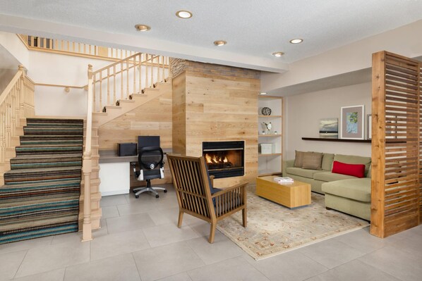 A modern living room with a wooden staircase, a fireplace, a sofa, and a coffee table. - Country Inn & Suites by Radisson, Springfield, OH (Springfield)