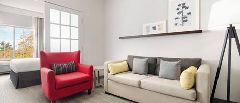 A modern living room with a red armchair, beige sofa, and a floor lamp.
