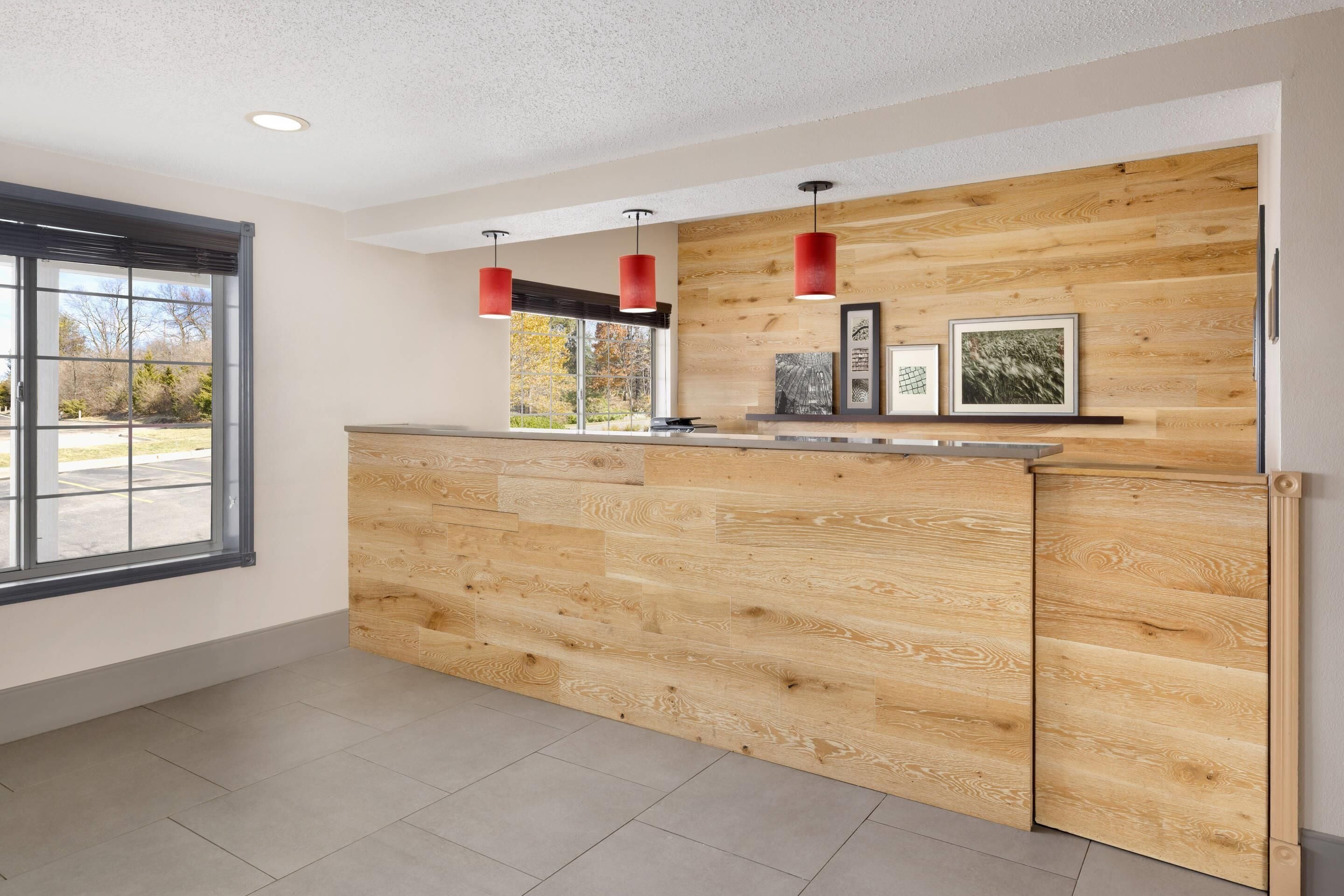 A modern reception area with a wooden counter, pendant lights, and framed pictures.