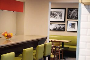 A restaurant interior with a counter, seating area, and wall-mounted artwork. - Country Inn & Suites by Radisson, Lincoln North Hotel and Conference Center, NE (Lincoln)