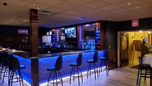 A bar area with a counter, stools, and a television screen.