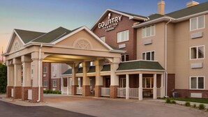 A Country Inn & Suites by Radisson building with a covered entrance, multiple windows, and a brick facade.