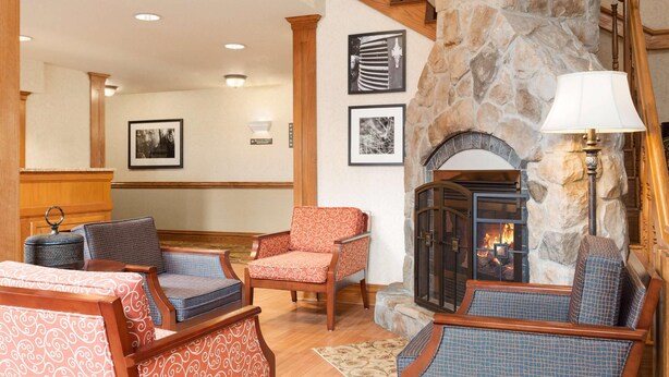 A cozy living room with a stone fireplace, wooden furniture, and framed artwork on the walls.