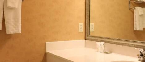 A bathroom with a white sink, a mirror, a toilet, and a towel rack.