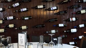A restaurant with a wall of wine bottles and a table set with wine glasses and a menu.