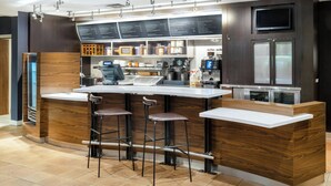 Eine moderne Bar mit Holztresen, Barhocker, einer Kaffeemaschine und einer Speisekarte.