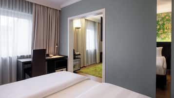 A hotel room with a bed, desk, chair, and a mirror reflecting the room.