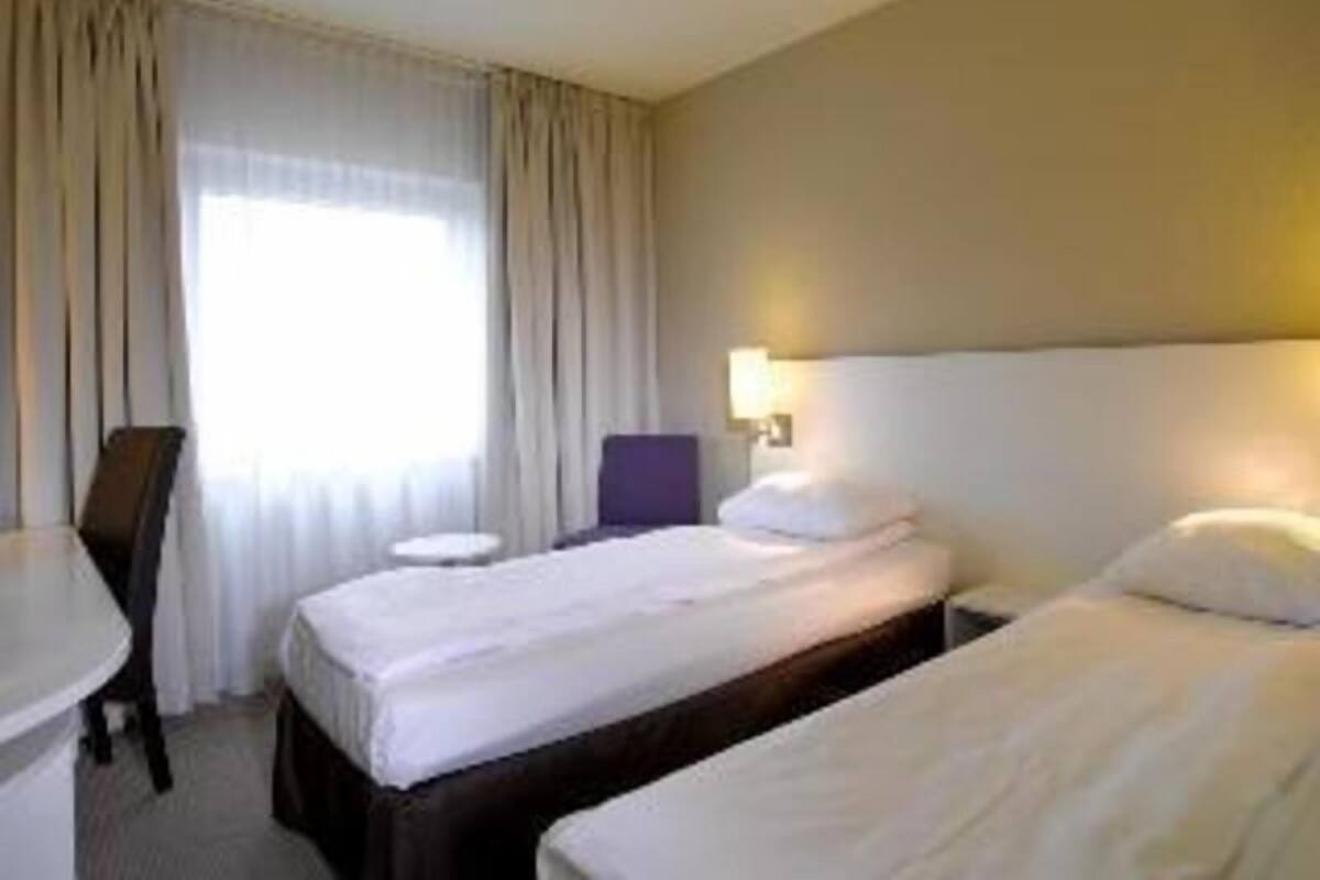 Een hotelkamer met twee bedden, een bureau en een stoel.