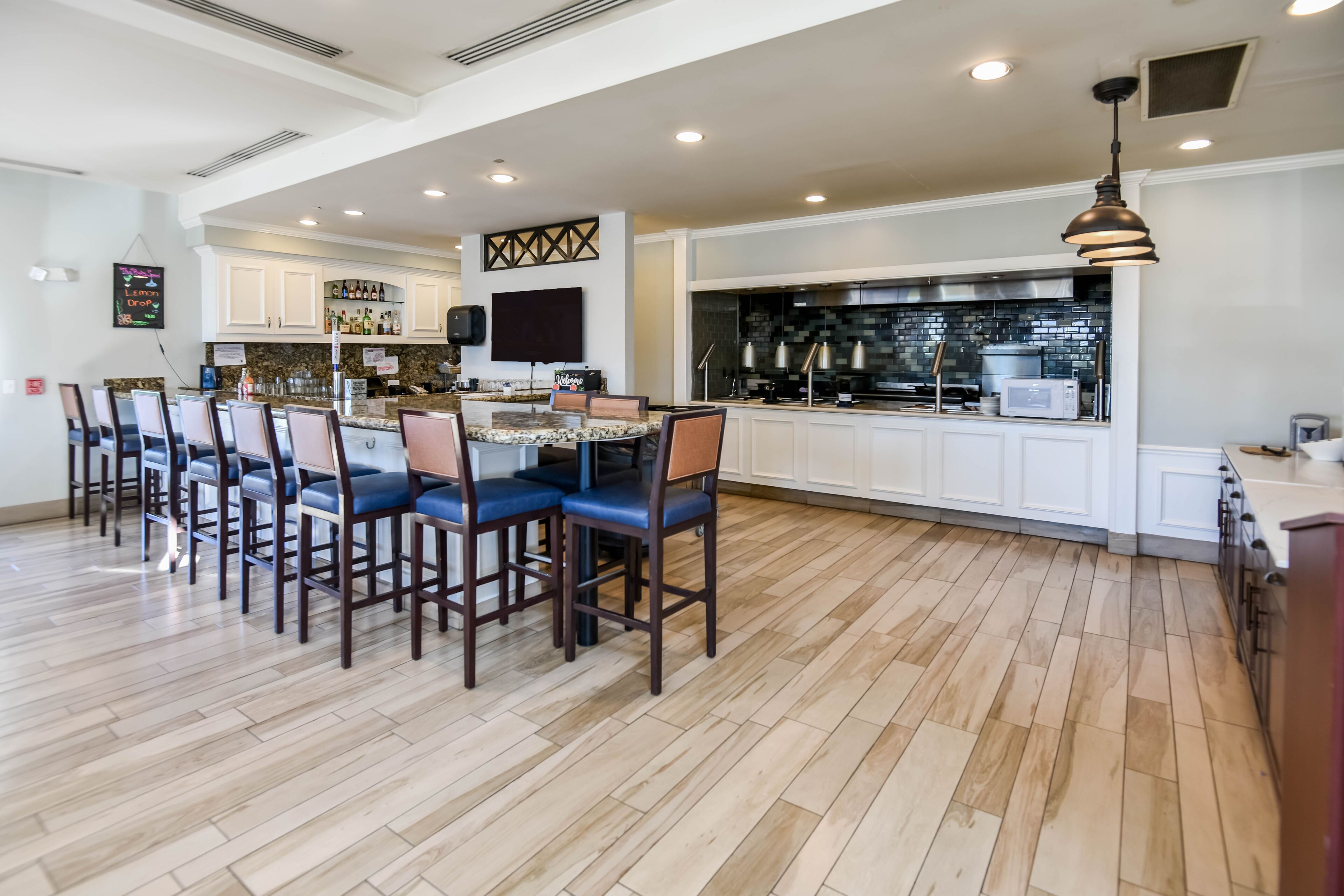 A spacious kitchen with a central island, white cabinetry, and a modern backsplash.
