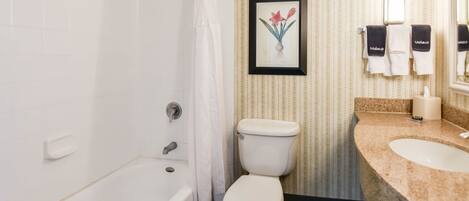 A bathroom with a bathtub, toilet, and vanity with a sink.