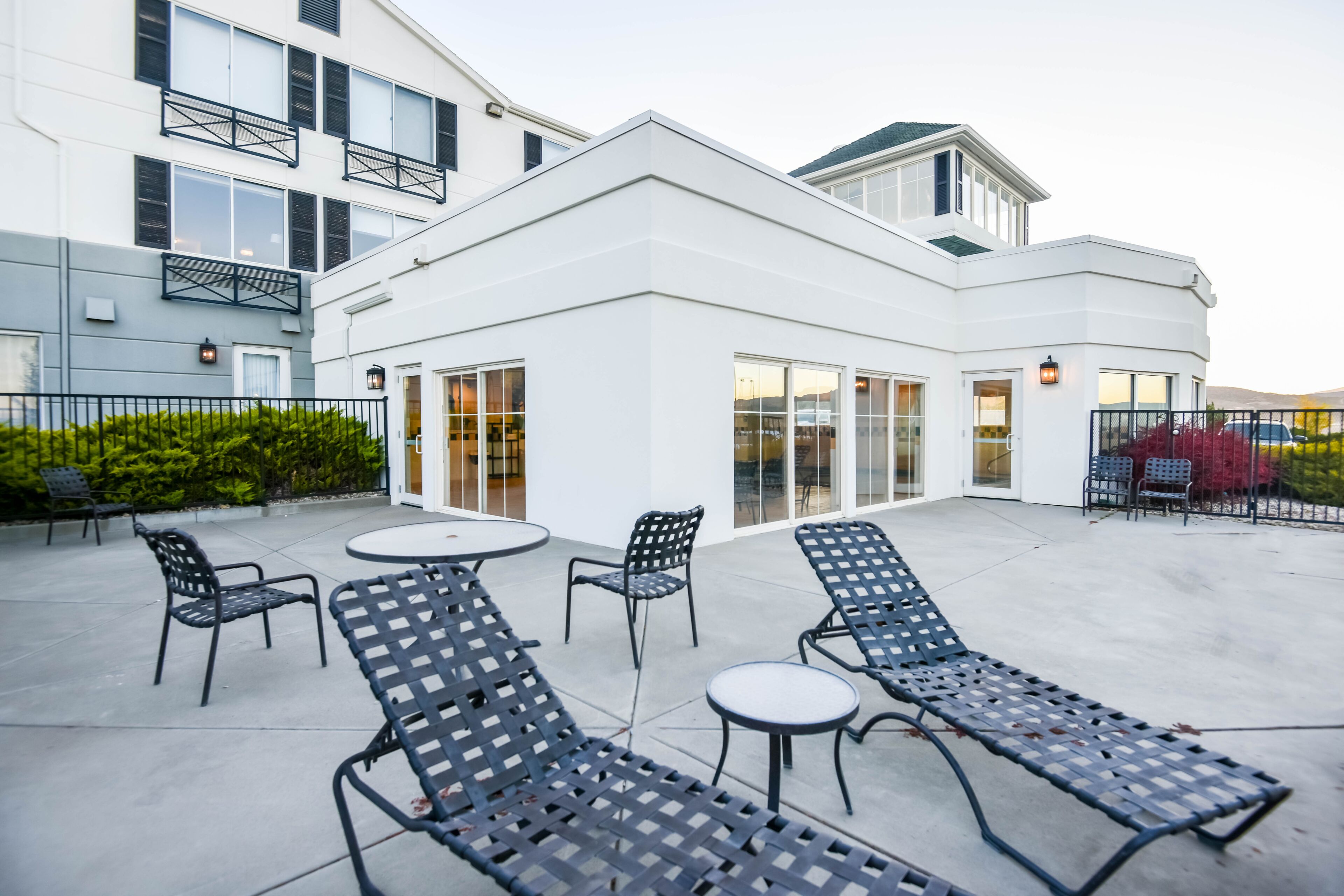 A modern building with a patio area featuring lounge chairs and tables.