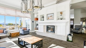 Amplia sala de estar con chimenea, ventanas grandes y muebles modernos.