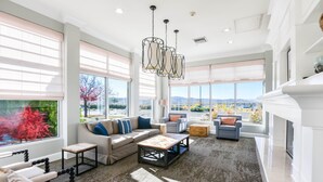 Amplia sala de estar con ventanas grandes, chimenea y muebles modernos.