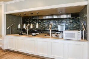 A kitchen with a white countertop, stainless steel appliances, and hanging pendant lights. - Shutters Hotel (Elko)