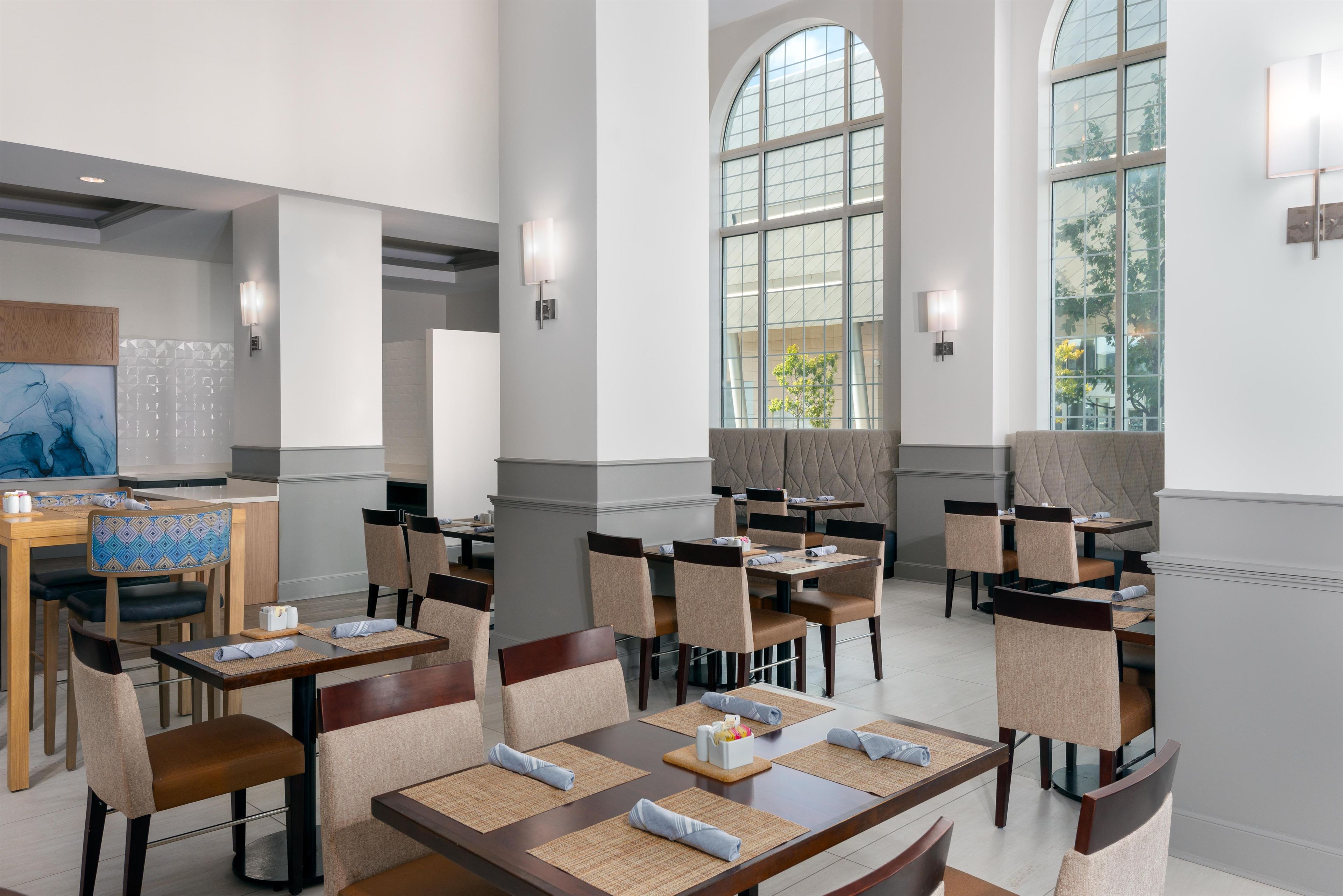 Un comedor moderno con techos altos, ventanas amplias y mobiliario contemporáneo.