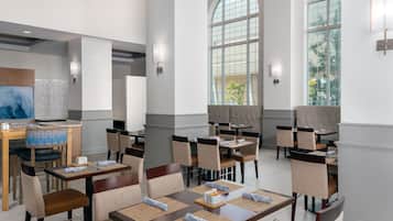 Un comedor moderno con techos altos, ventanas amplias y mobiliario contemporáneo.