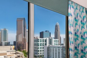 A cityscape through a window with modern buildings, a clear sky, and a patterned curtain. - Hilton Garden Inn Charlotte Uptown (Charlotte)