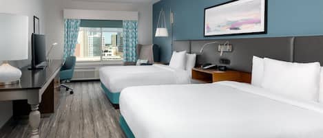 Habitación de hotel con dos camas, un escritorio, una silla, un televisor y una ventana con cortinas.