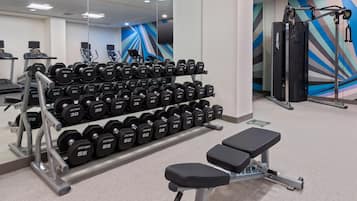 Une salle de sport équipée de matériel de musculation, de tapis de course et d’un banc.